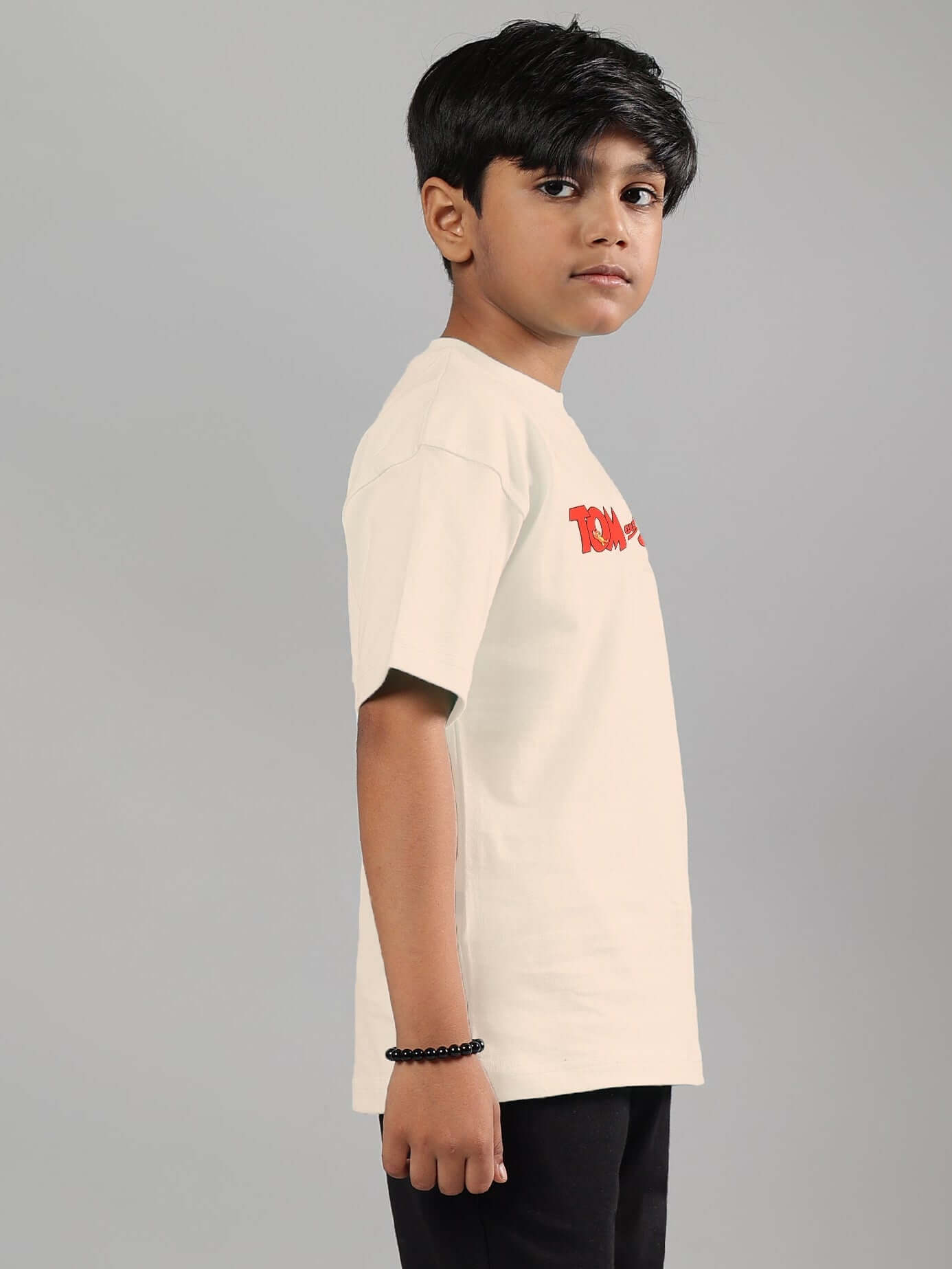 Side view of a child wearing an off-white Tom & Jerry t-shirt, suitable for both boys and girls, made by experienced tailors at DUDS.