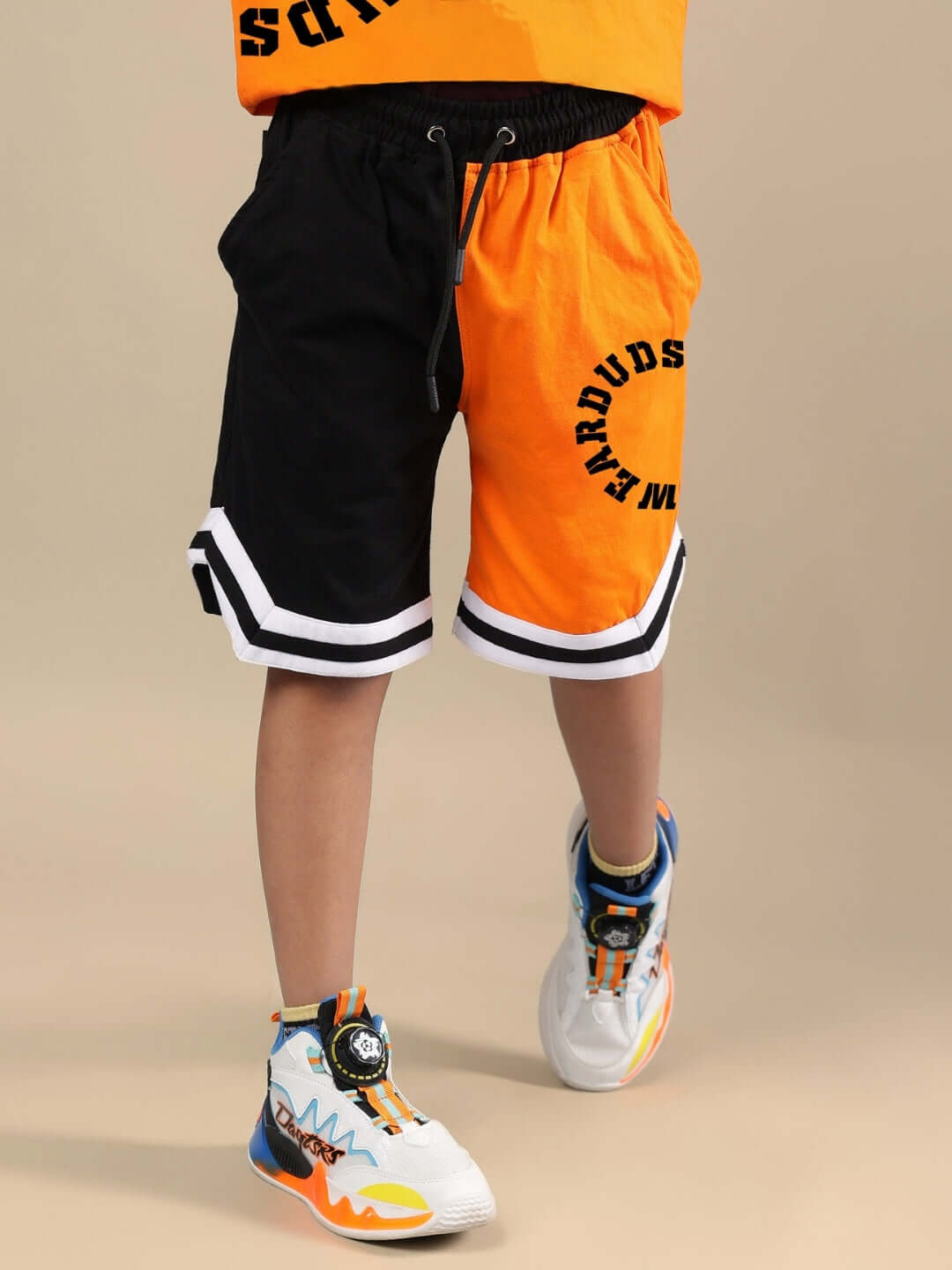 TRACK & FIELD CO-ORD FOR BOYS & GIRLS ORANGE BLACK Child wearing orange and black track and field co-ord set from DUDS, showcasing sporty shorts design, suitable for boys and girls.