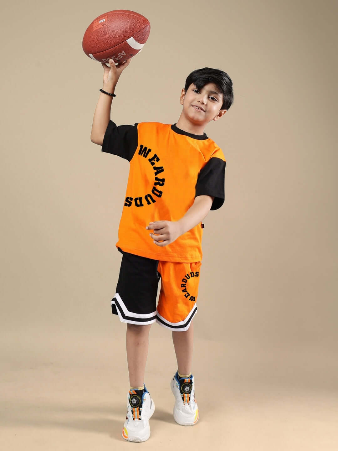 TRACK & FIELD SHORTS FOR BOYS & GIRLS BLACK-ORANGE Boy wearing black-orange track & field shorts, holding a football.