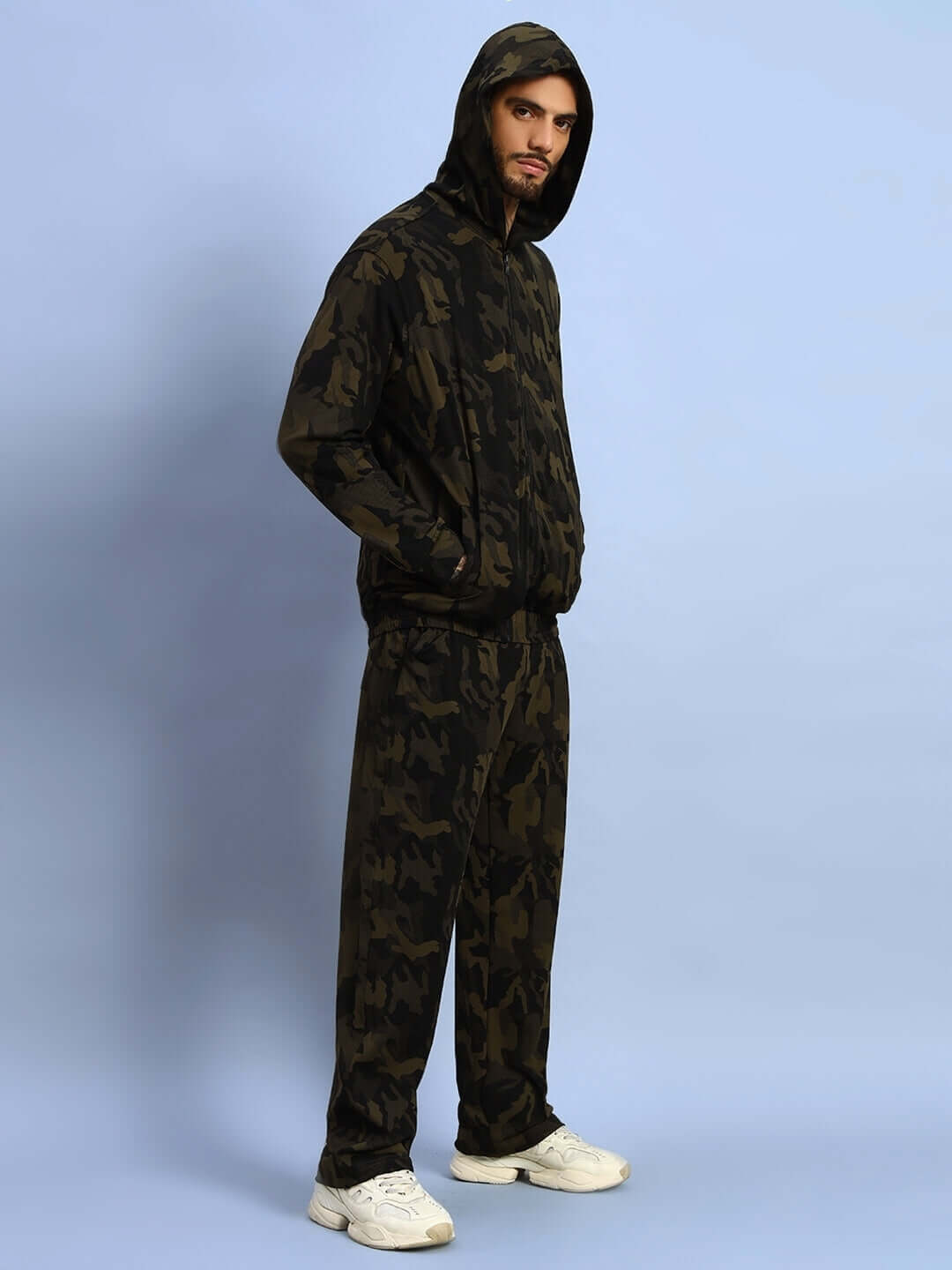 Model wearing TRENCH CO-ORD SET CAMOUFLAGE GREEN with hooded top and matching pants made of polyester-spandex blend.