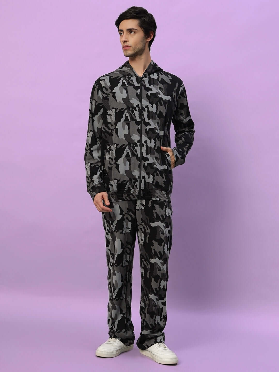 Model wearing Trench Relaxed Pant Jogger in camo navy pattern by DUDS, standing against a light purple background.