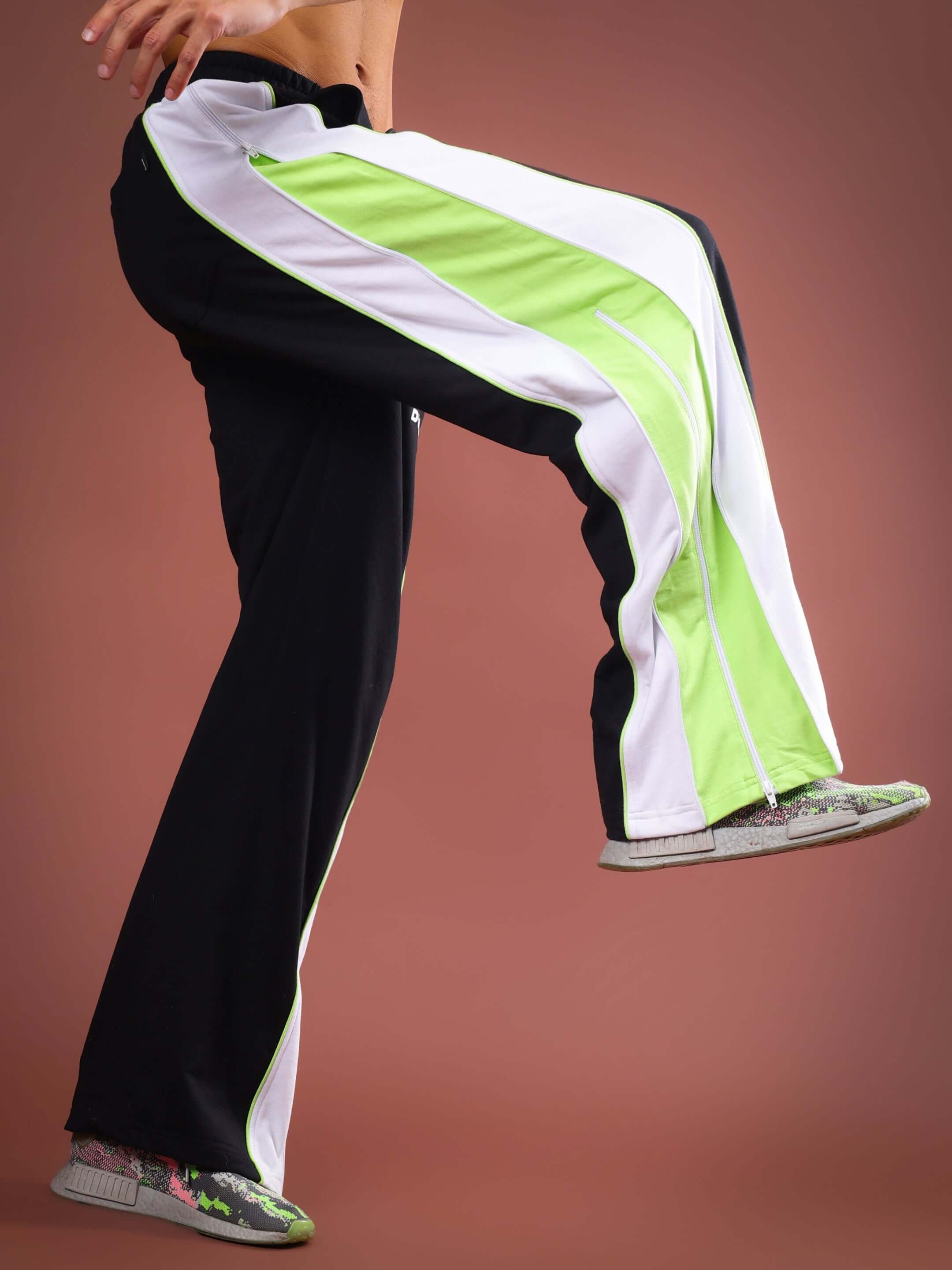 Model wearing TRIUMPH Multi Zipper Joggers in black neon with custom fit option, showcasing dynamic design and vibrant colors.