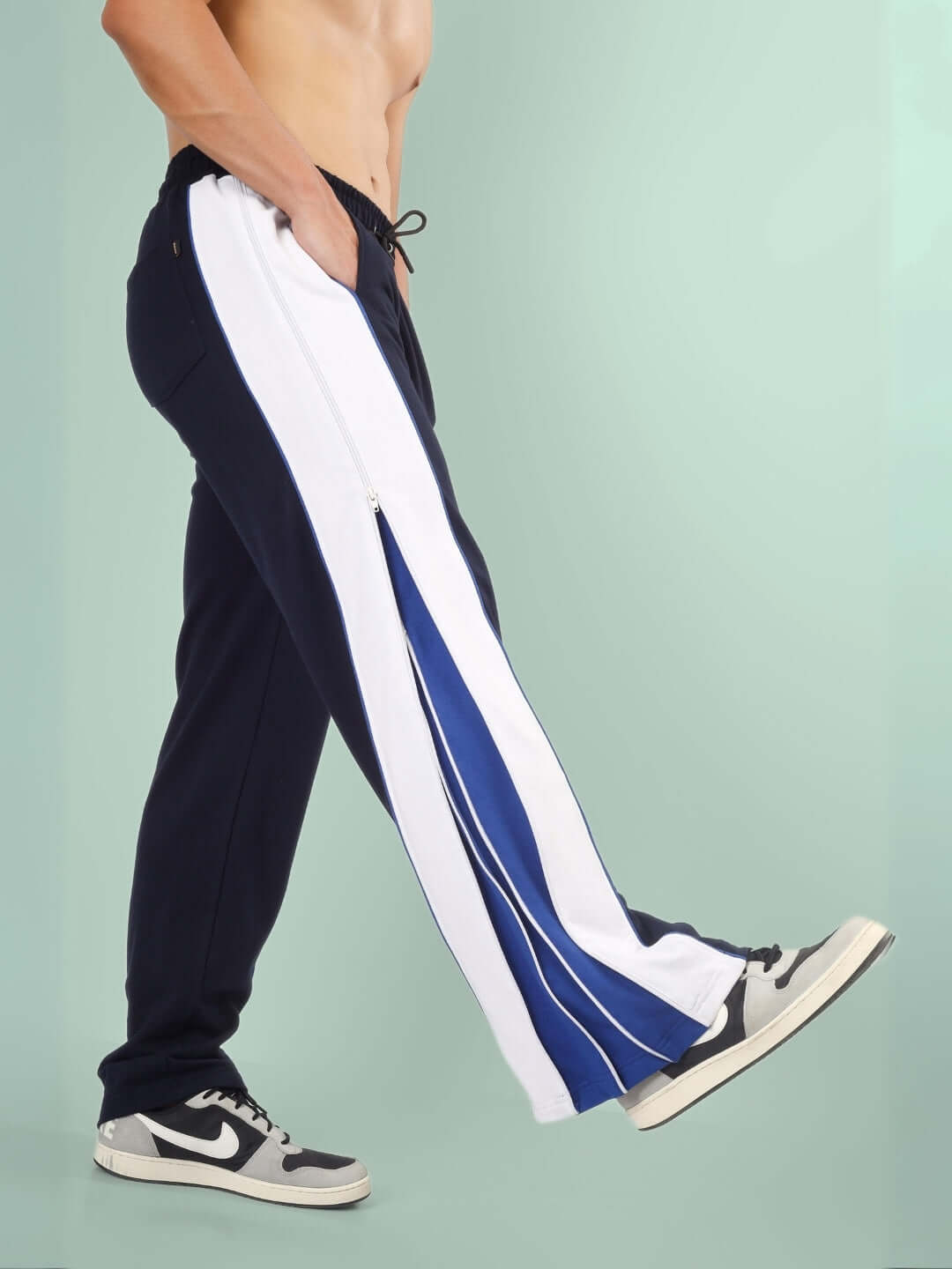 Side profile of TRIUMPH Multi Zipper Joggers in black with blue and white stripes, worn with sneakers, showcasing custom fit option.