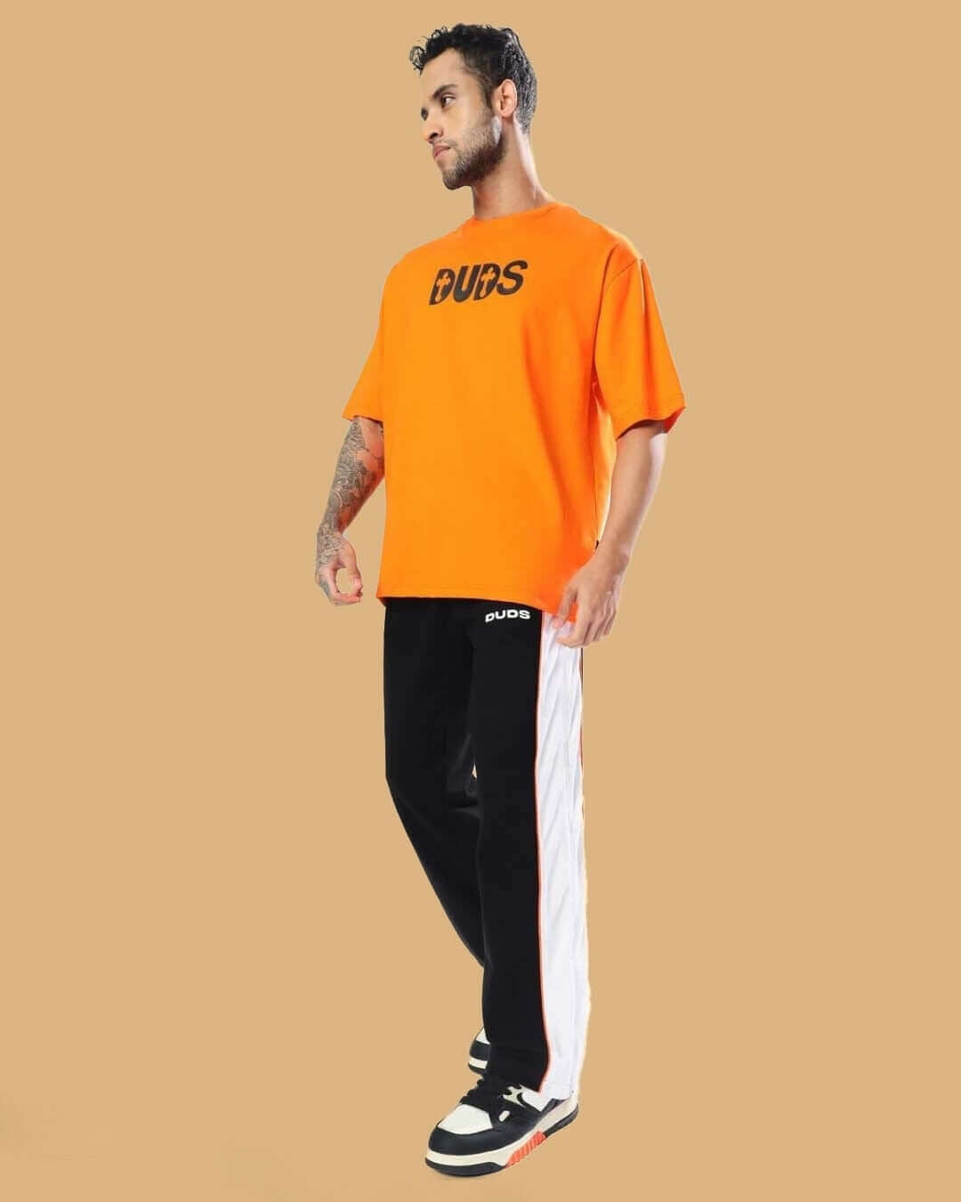 Man wearing Triumph Multi Zipper Joggers in Black Orange by DUDS, styled with an orange DUDS t-shirt, perfect for a customized fit.