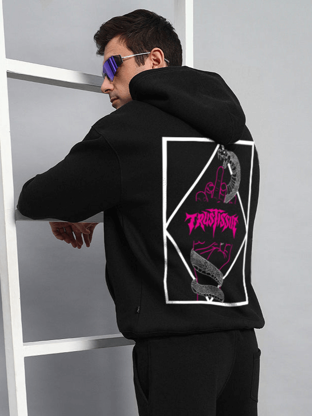 Man wearing TRUSTISSUE Oversized Black Hoodie with unique graphic design on the back, customizable size available, stylish streetwear