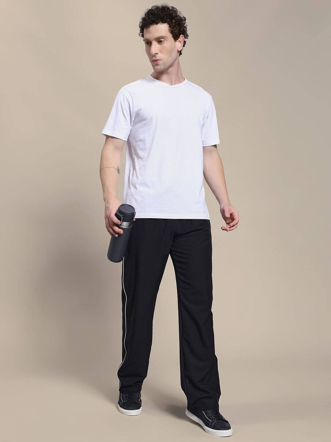 Man wearing TURBO TRACK RELAXED-FIT JOGGERS BLACK paired with a white t-shirt, holding a water bottle.