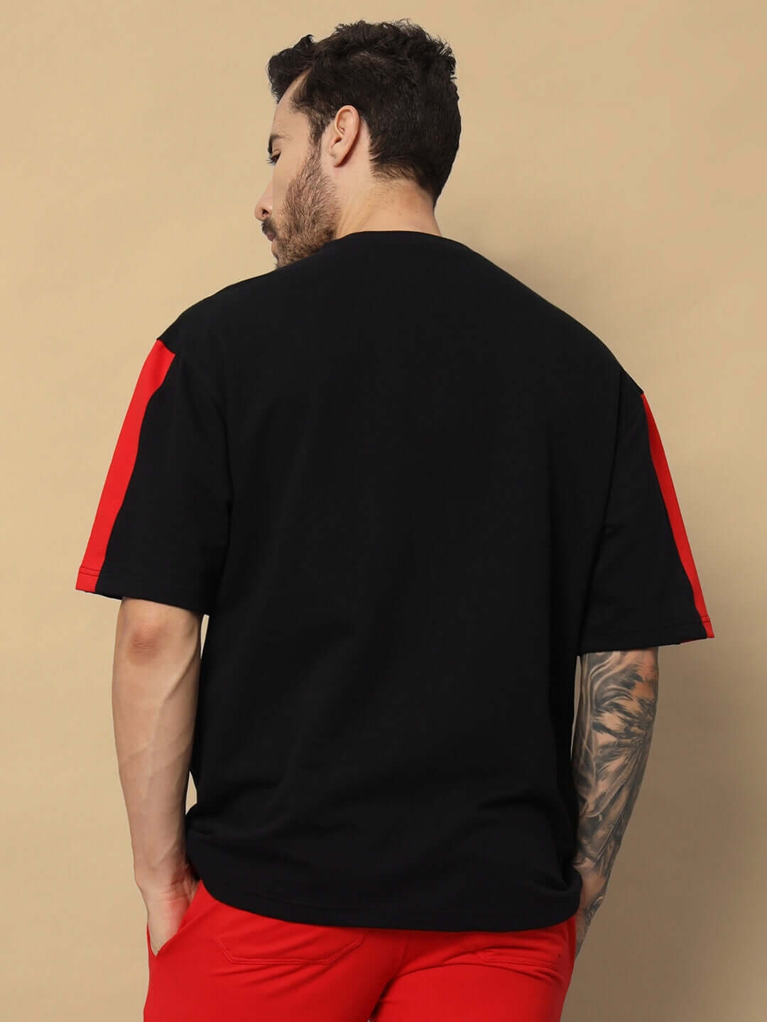 Back view of a model wearing a black TURNING DREAMS REFLECTOR oversized T-shirt with red accents, made from premium cotton blend.