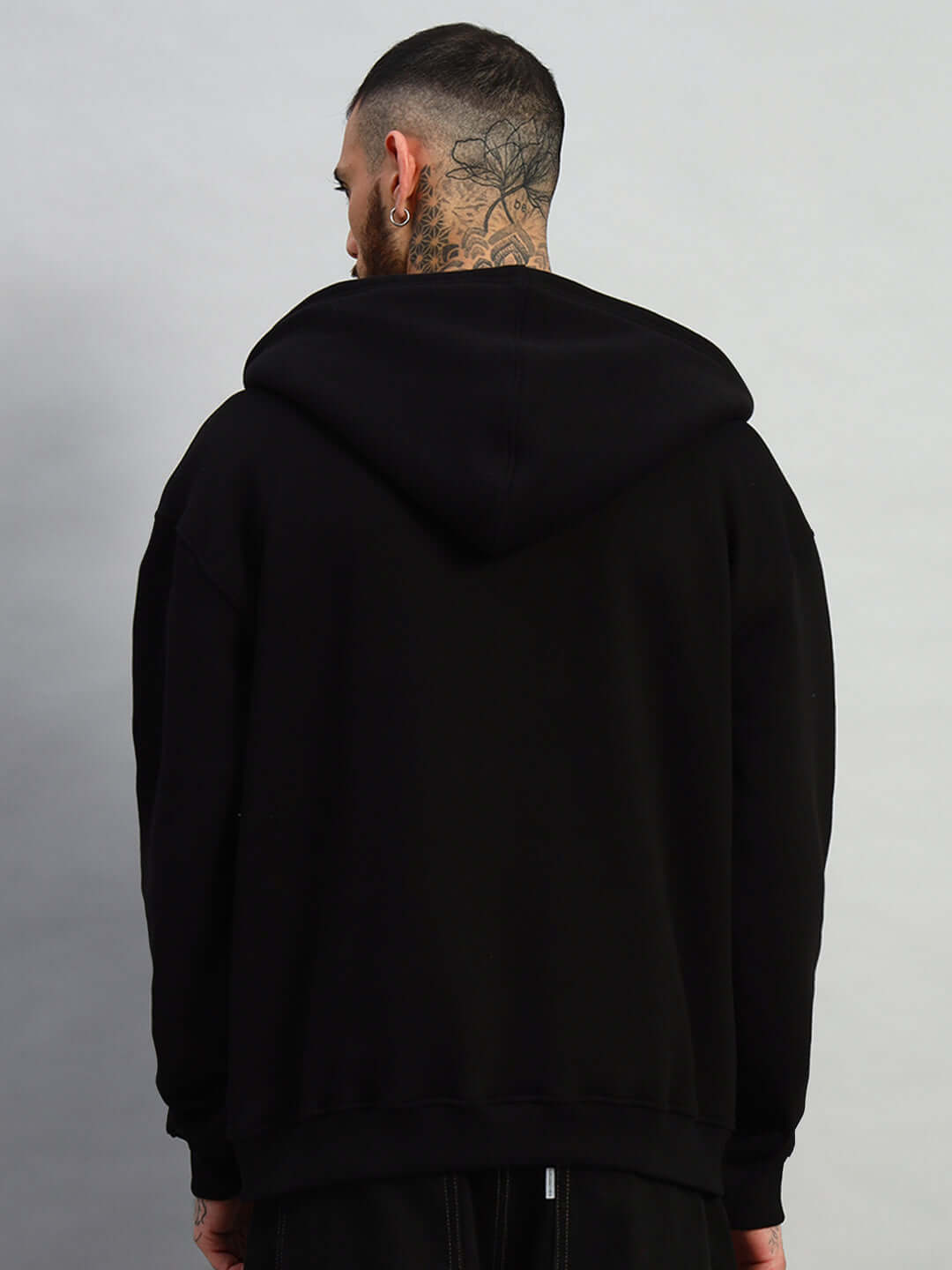 Back view of model wearing WEARDUDS TWO FOLD ZIPPER HOODIE BLACK with hood up, showing detail and fit.