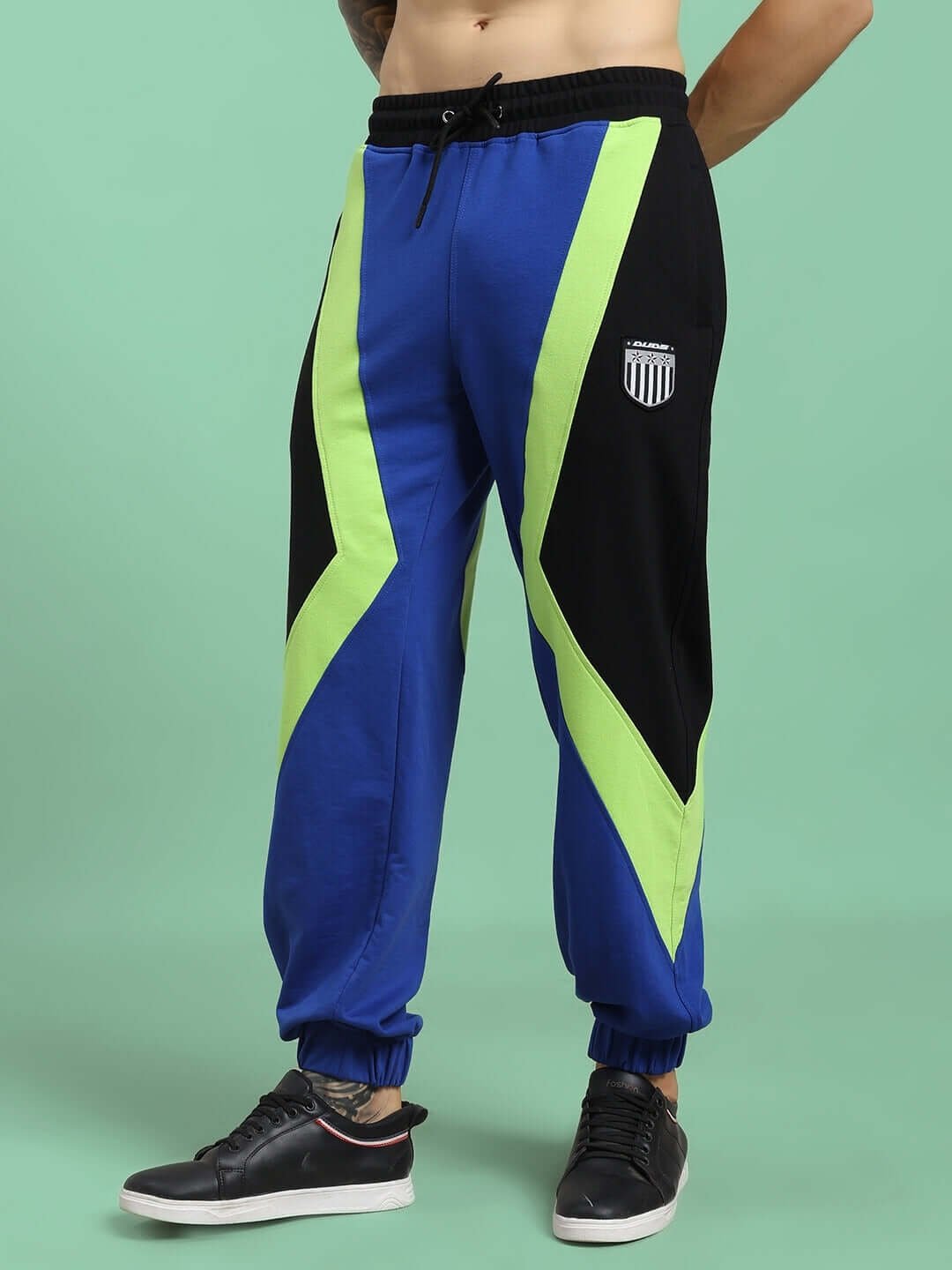 Person wearing ULTRA COLORBLOCK RELAXED-FIT JOGGERS BLUE-BLACK with neon accents, showcasing streetwear style.