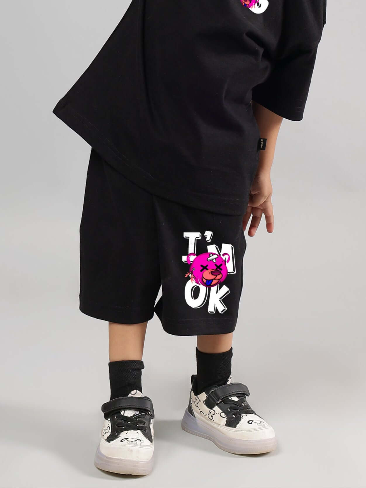 Child wearing I M OK SHORTS FOR BOYS GIRLS BLACK with bold graphic design.