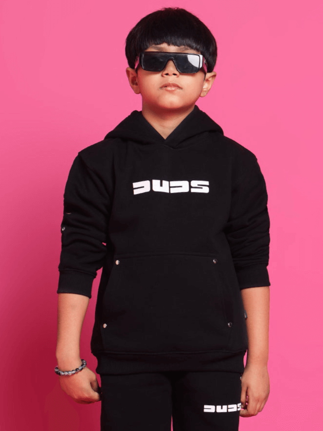 Young boy wearing SHOOTER HOODIES FOR BOYS GIRLS BLACK with sunglasses, showcasing a trendy and sporty look against a pink background.