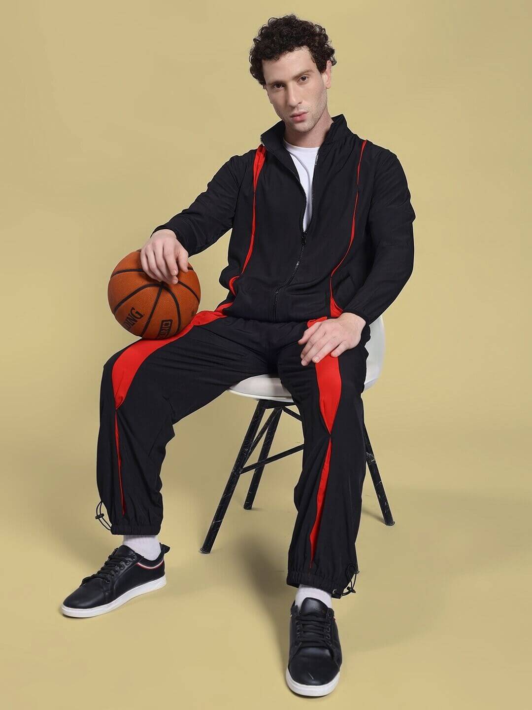 Man wearing UNISON RELAXED FIT JACKET BLACK RED, holding basketball, showcasing stylish casual fashion.