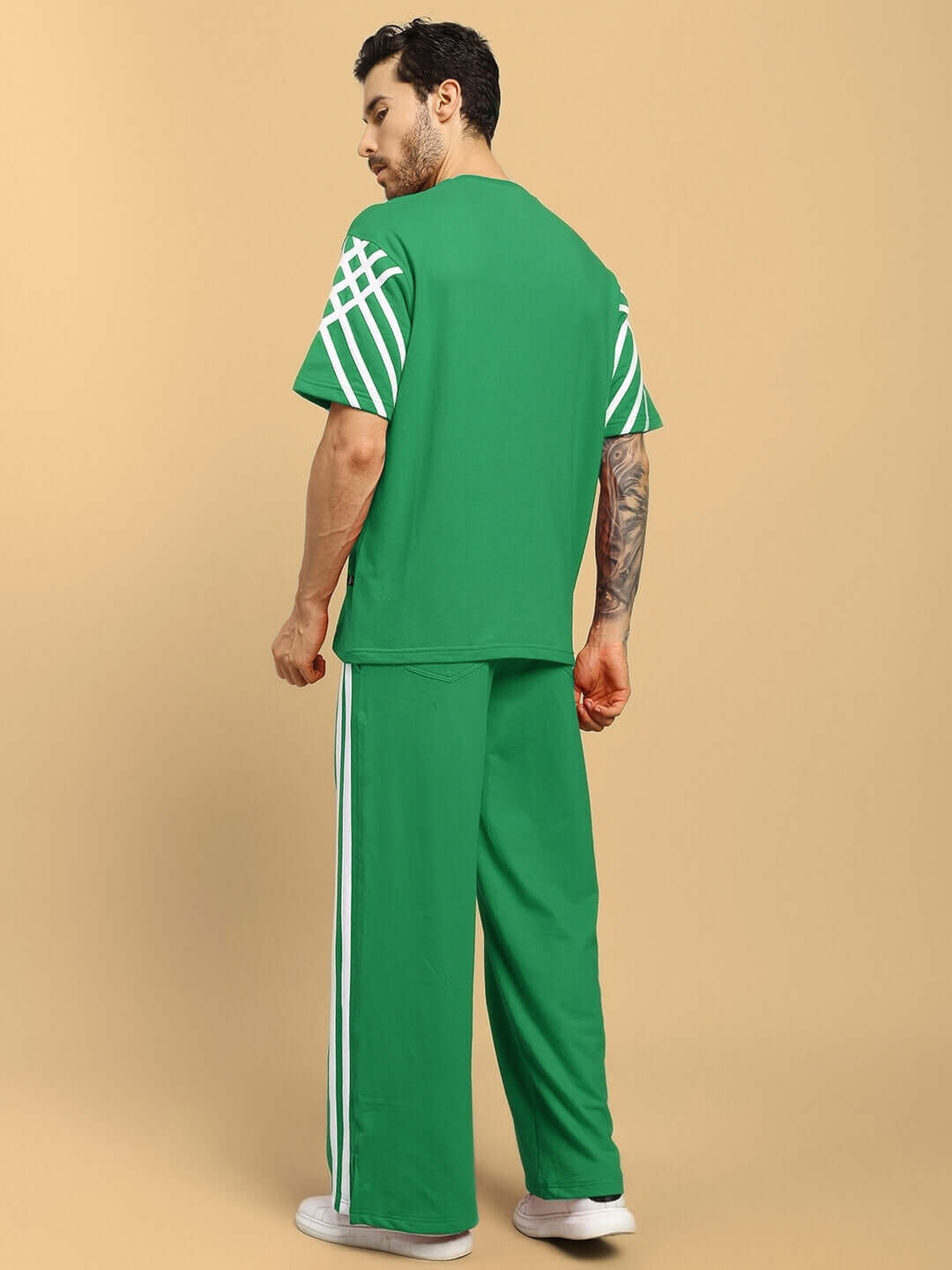 Model wearing UNITED STRIPE CO-ORD SET GREEN with white stripe detailing, showcasing back view of stylish streetwear outfit.