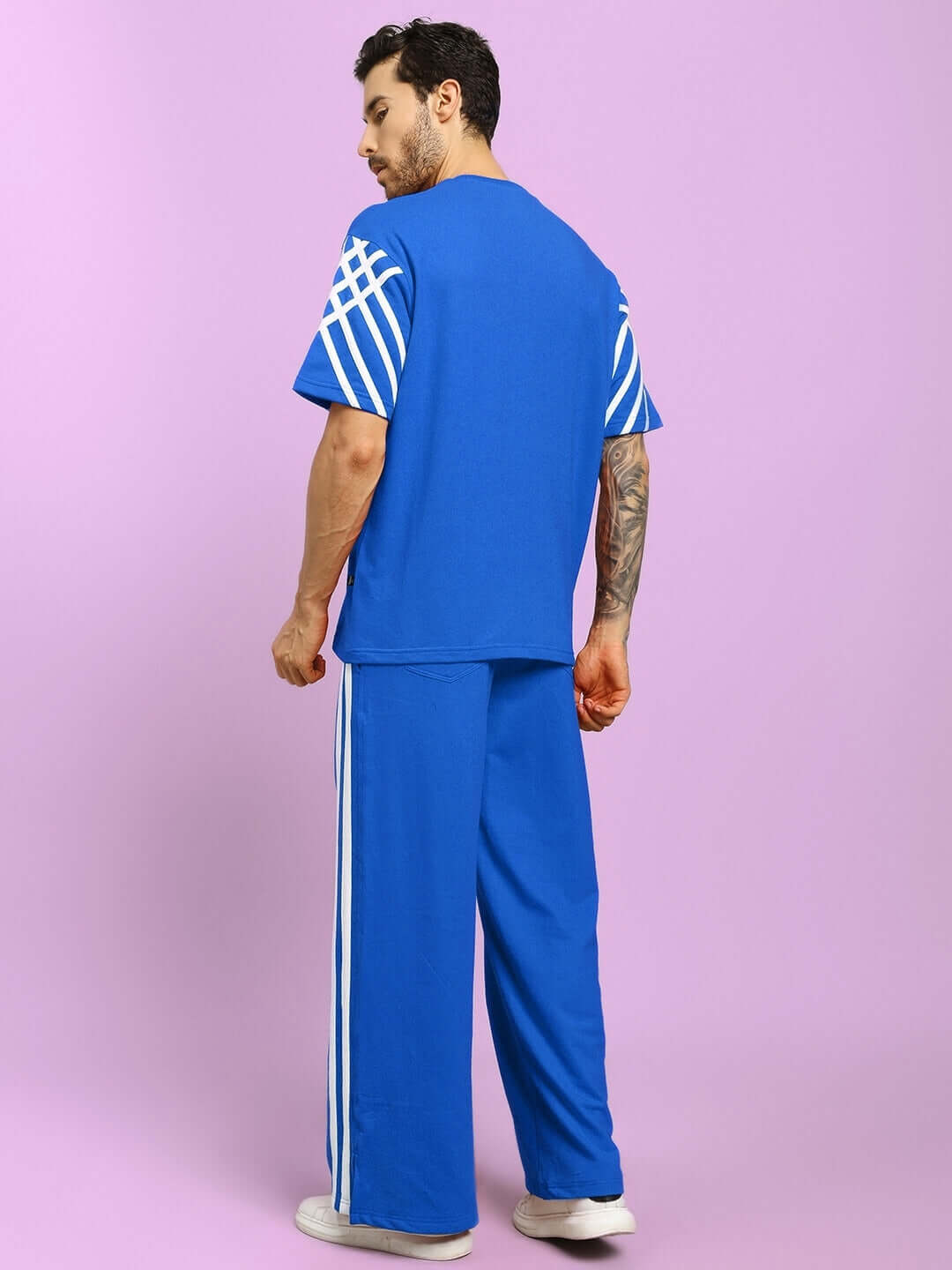 Man wearing UNITED STRIPE CO-ORD SET BLUE MEN with striped sleeves and pants in a vibrant blue hue, perfect for streetwear style.