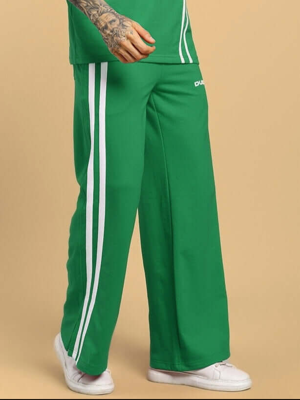 Model wearing UNITED STRIPE JOGGERS GREEN MEN with bold stripes, showcasing sporty streetwear style.