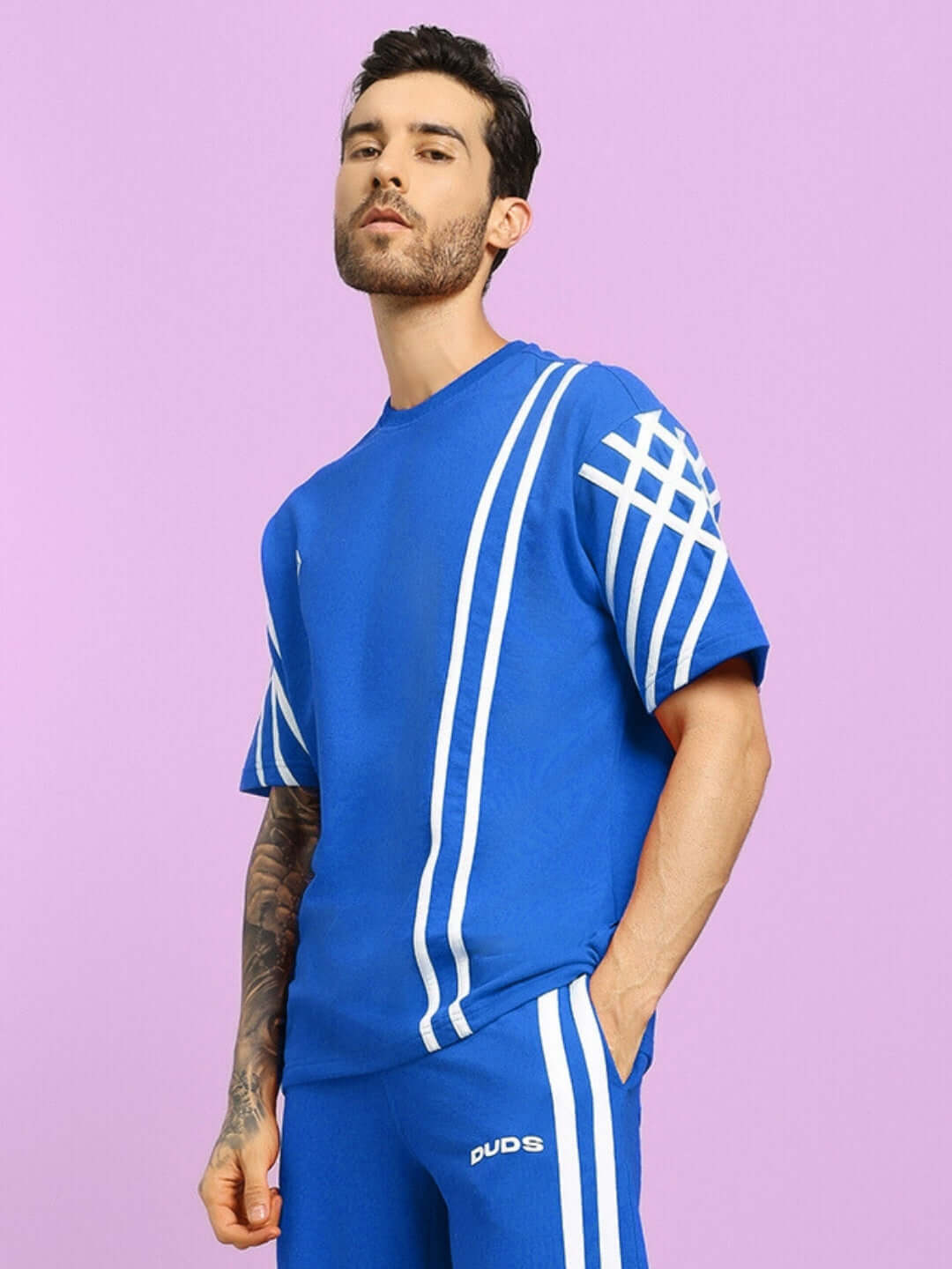 Model wearing UNITED STRIPE OVER-SIZED T-SHIRT in blue, made from 97% cotton French terry and 3% elastane, featuring white stripe design.