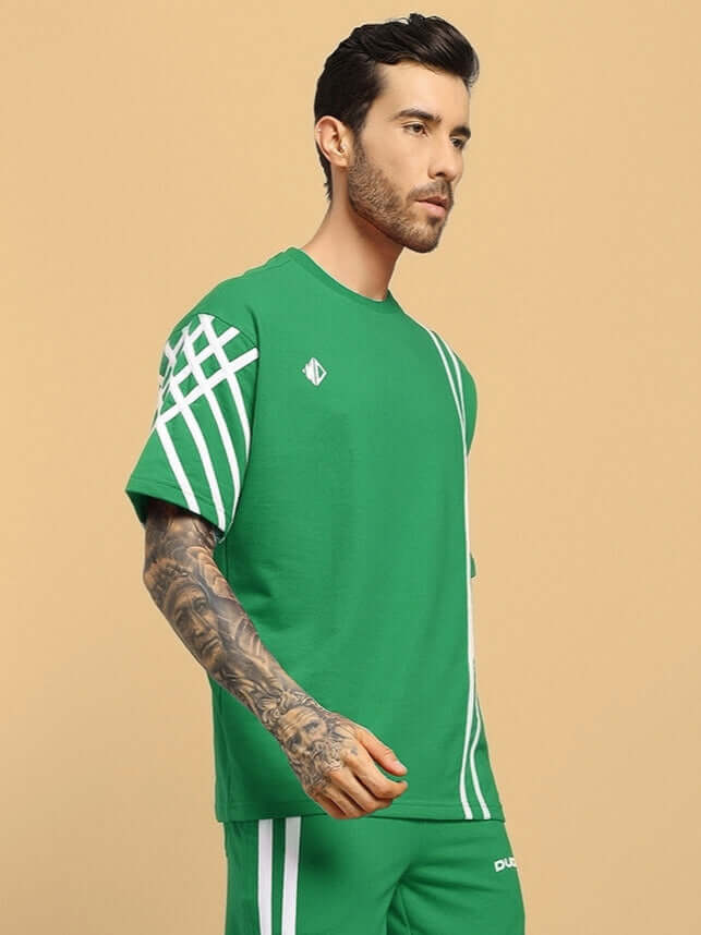 Model wearing UNITED STRIPE OVER-SIZED T-SHIRT in green with premium heavy gauge cotton fabric, featuring white stripe details.