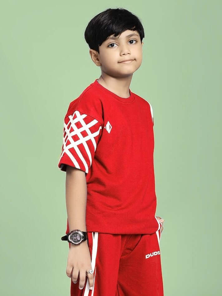 Boy wearing a UNITED STRIPE T-SHIRT FOR BOYS AND GIRLS RED against a green background, showcasing vibrant color and stripe design.