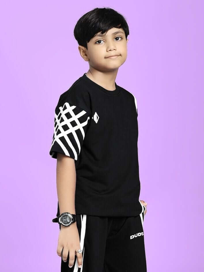 Boy wearing UNITED STRIPE T-SHIRT FOR BOYS AND GIRLS BLACK with white stripe design, standing against a purple background.