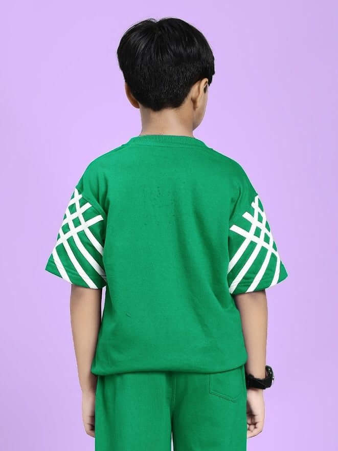 Child wearing UNITED STRIPE T-SHIRT FOR BOYS AND GIRLS GREEN with stripe accents, showcasing back view against a light purple background.