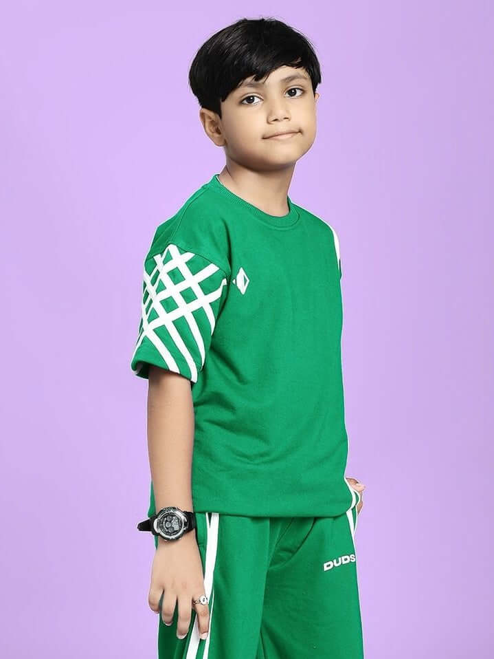 Boy wearing UNITED STRIPE T-SHIRT FOR BOYS AND GIRLS GREEN with stripe accents on purple background