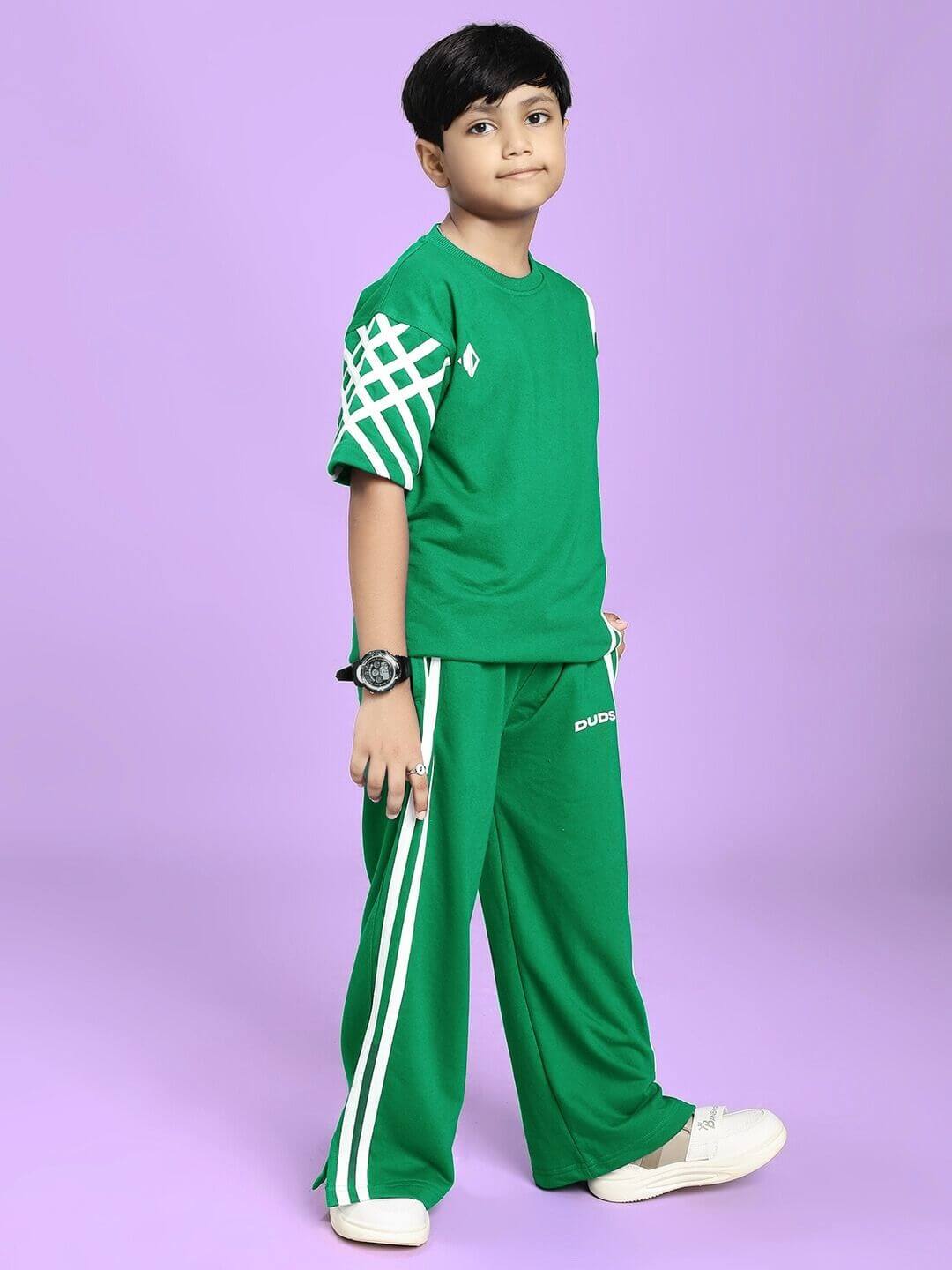 Child wearing UNITED STRIPE CO-ORD SET FOR BOYS GIRLS GREEN with stripe design on sleeves and sides, standing against a purple background.