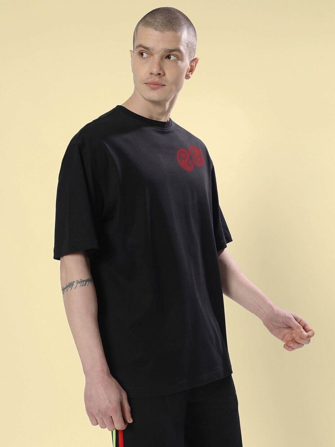 Person wearing URBAN CULTURE PRINTED OVERSIZED T-SHIRT BLACK showcasing street fashion in a casual urban setting.