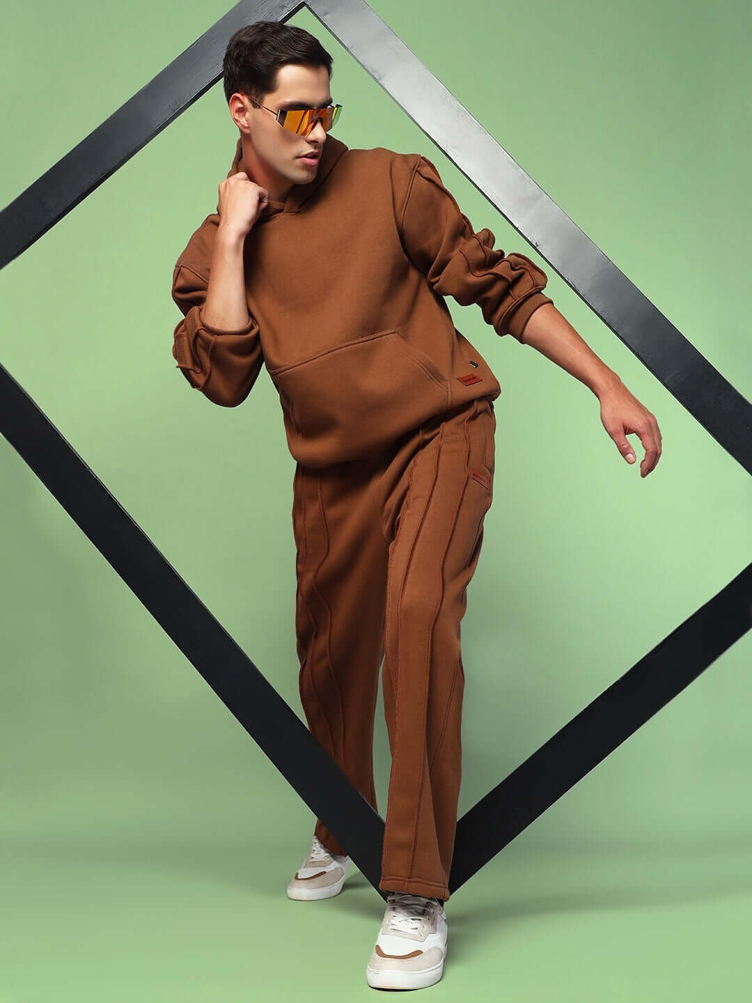 Man wearing URBAN SOLID PLATED FLEECE CO-ORD BROWN with hoodie and joggers on geometric backdrop