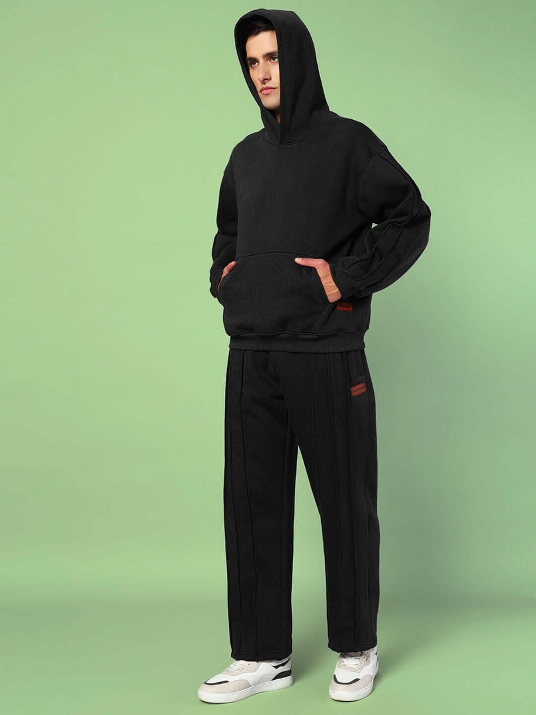 Man wearing URBAN FLEECE CARGO PANTS BLACK with black hoodie against green background