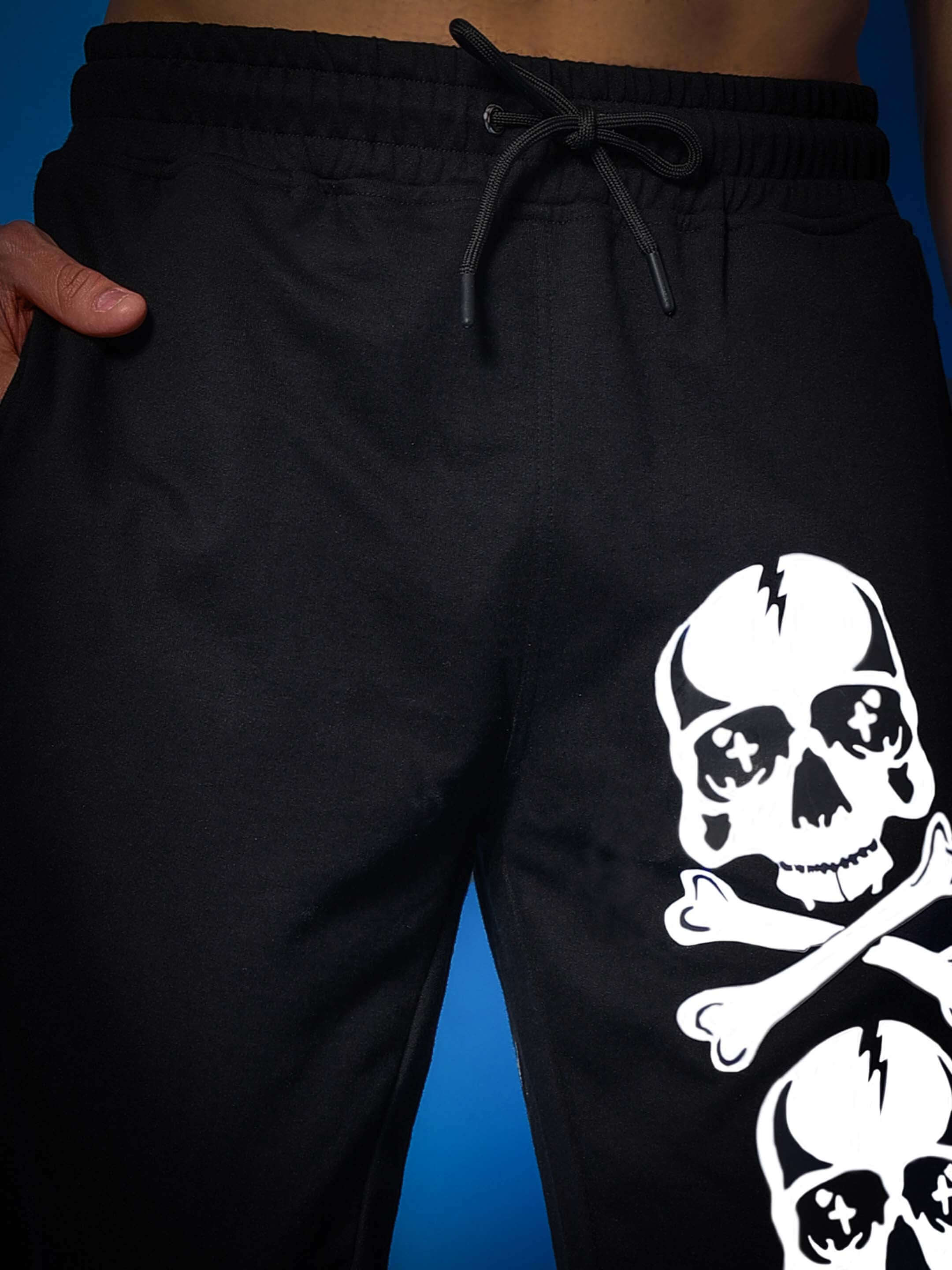 Black jogger pants with a skull and crossbones design on the leg, featuring an adjustable drawstring waistband.