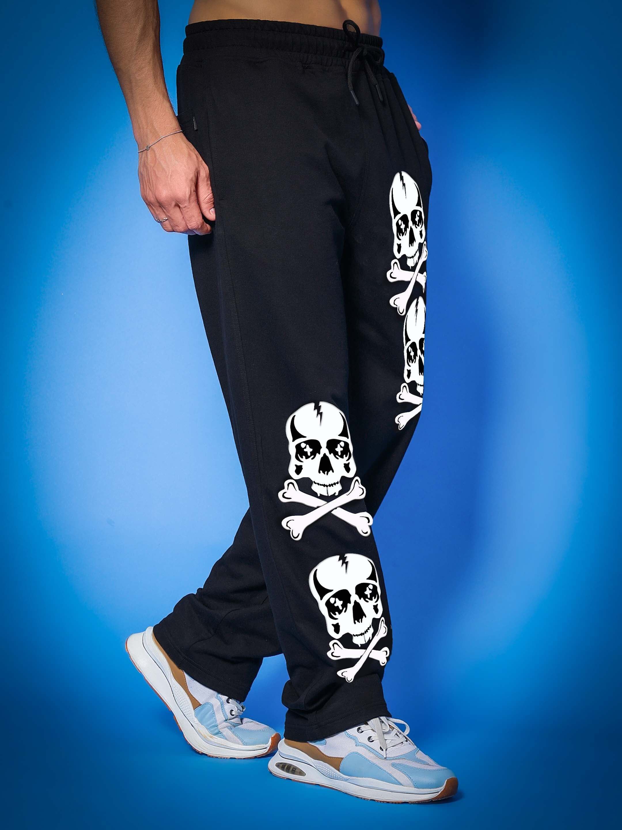 Black jogger pants with skull design, worn by a model against a blue backdrop, featuring customization option from DUDS.