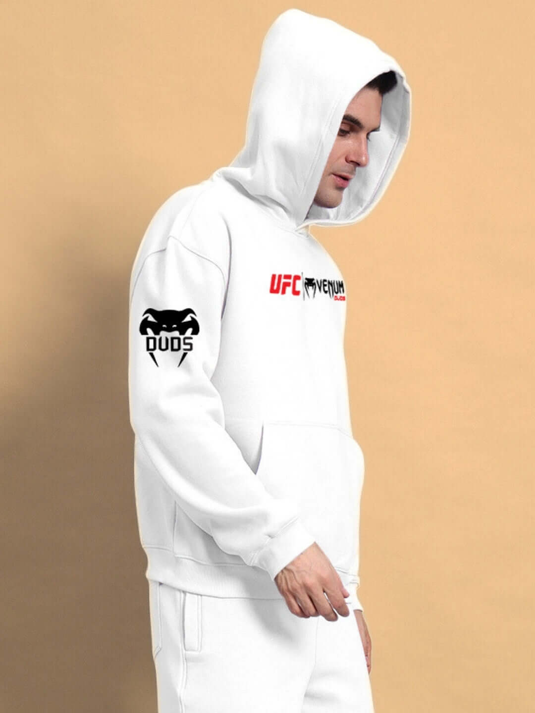 Person wearing WEARDUDS VENUM FLEECE HOODIE WHITE with hood up, showing side logos, on a beige background.