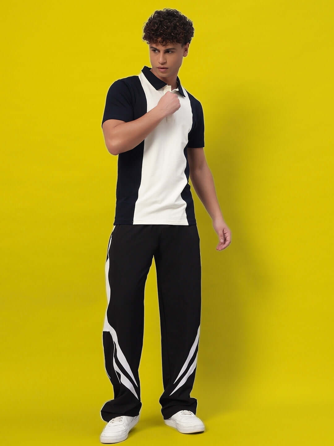 Model wearing black and white versatile parachute cargo pants on a yellow background.