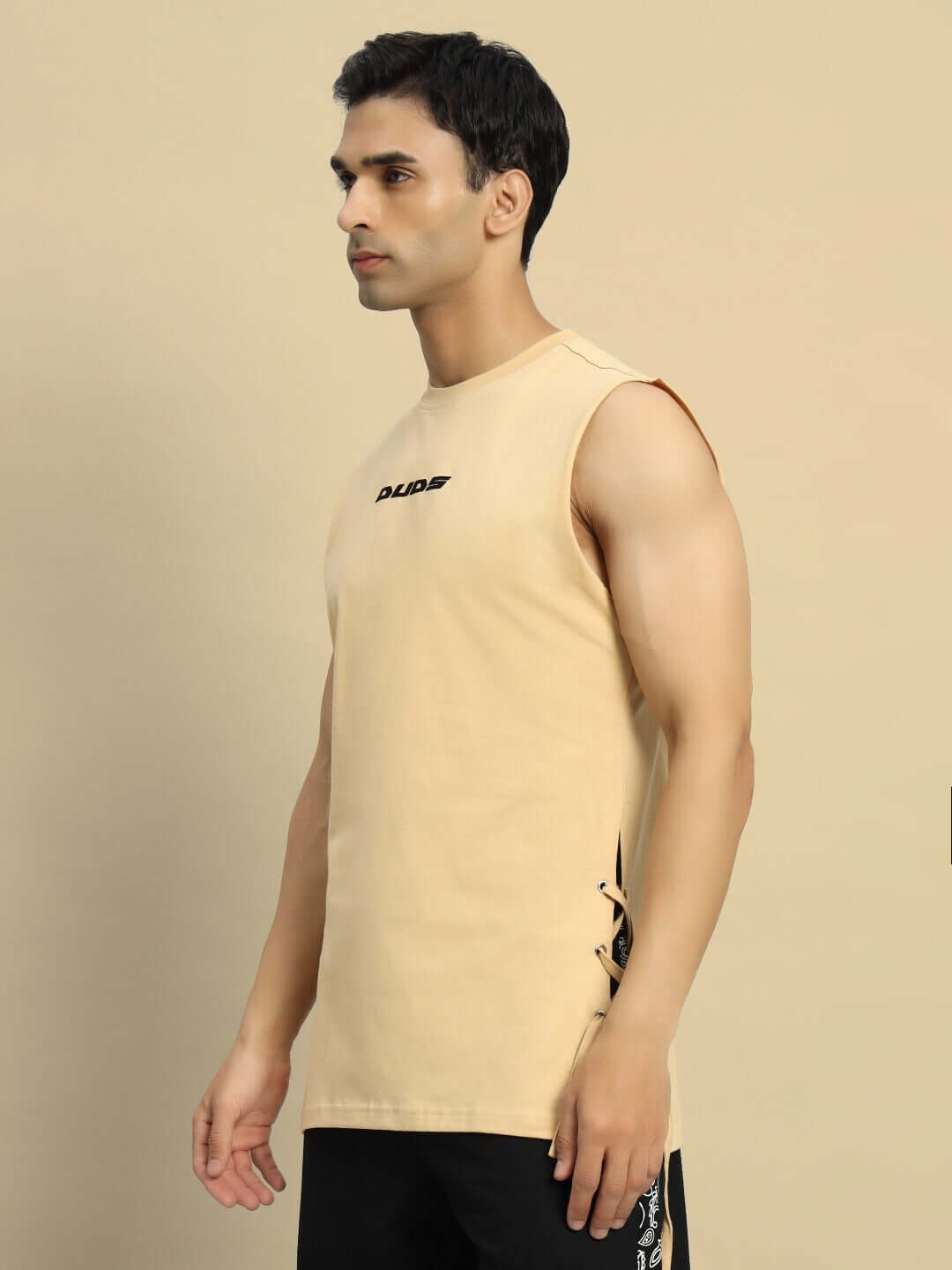 Model wearing Vertex relaxed fit sleeveless beige t-shirt by DUDS, showcasing a custom fit option available for prepaid orders.