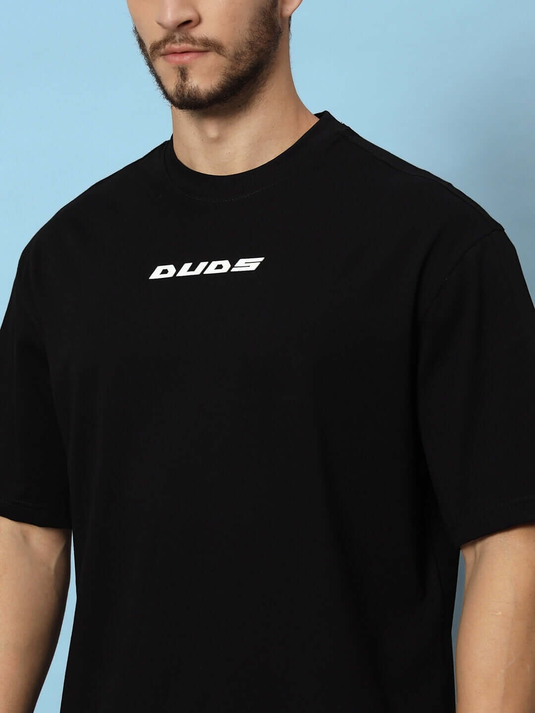 Man wearing a black Victory over-sized t-shirt with DUDS logo.