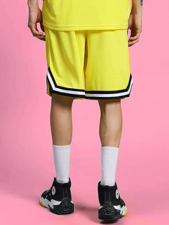 Back view of person wearing VIGOR REGULAR FIT SHORTS YELLOW in a sporty look against a pink background