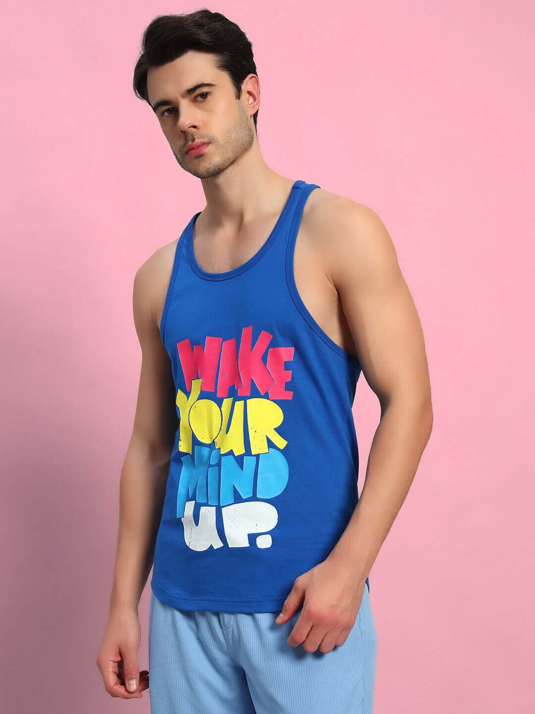 Person wearing WAKE UP GYM T-SHIRT ROYAL BLUE with colorful print against pink background.