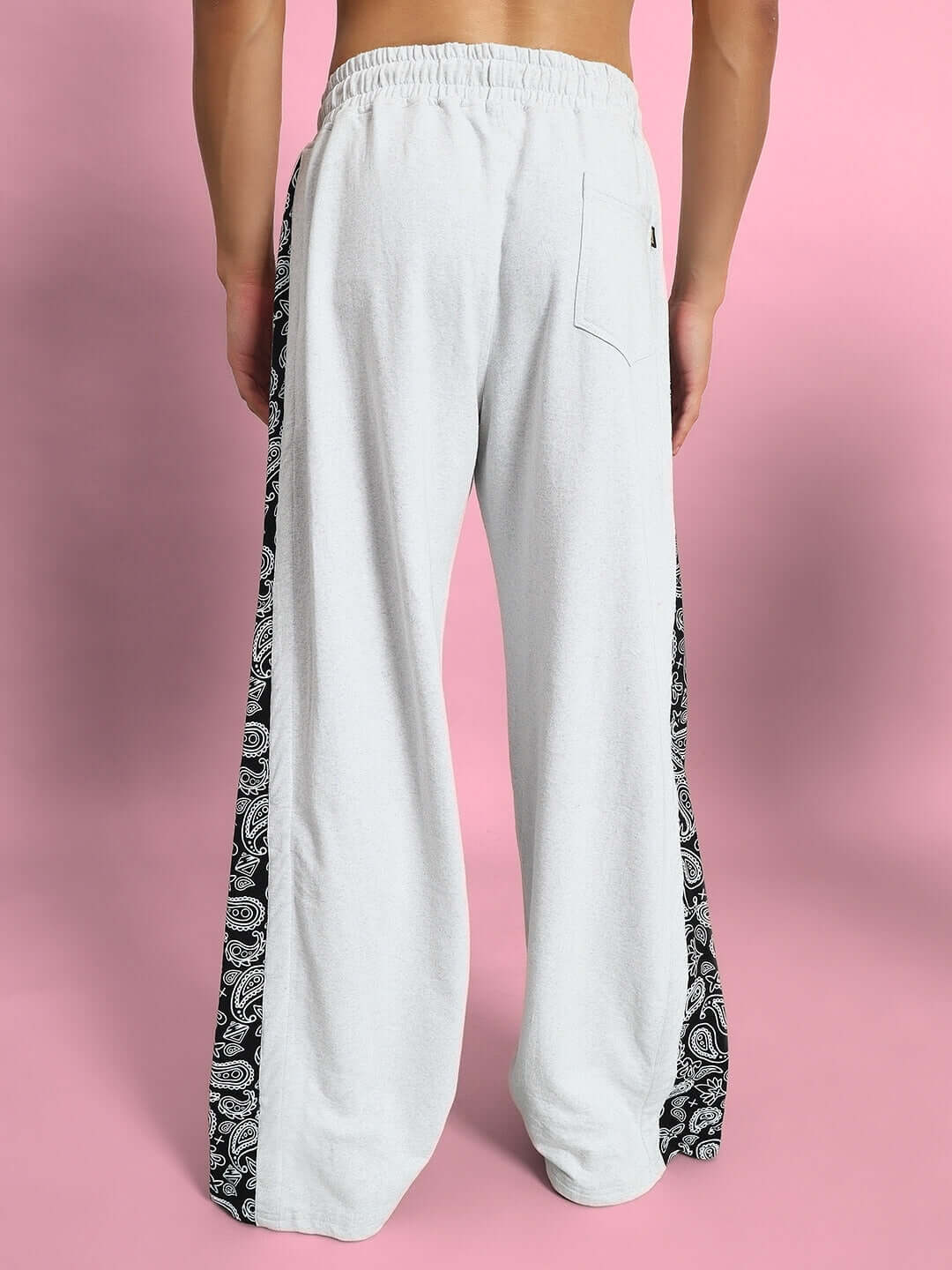 Model wearing Waltz Relaxed Fit Joggers in Melange Grey with paisley side panels, showcasing fit and design on pink background.