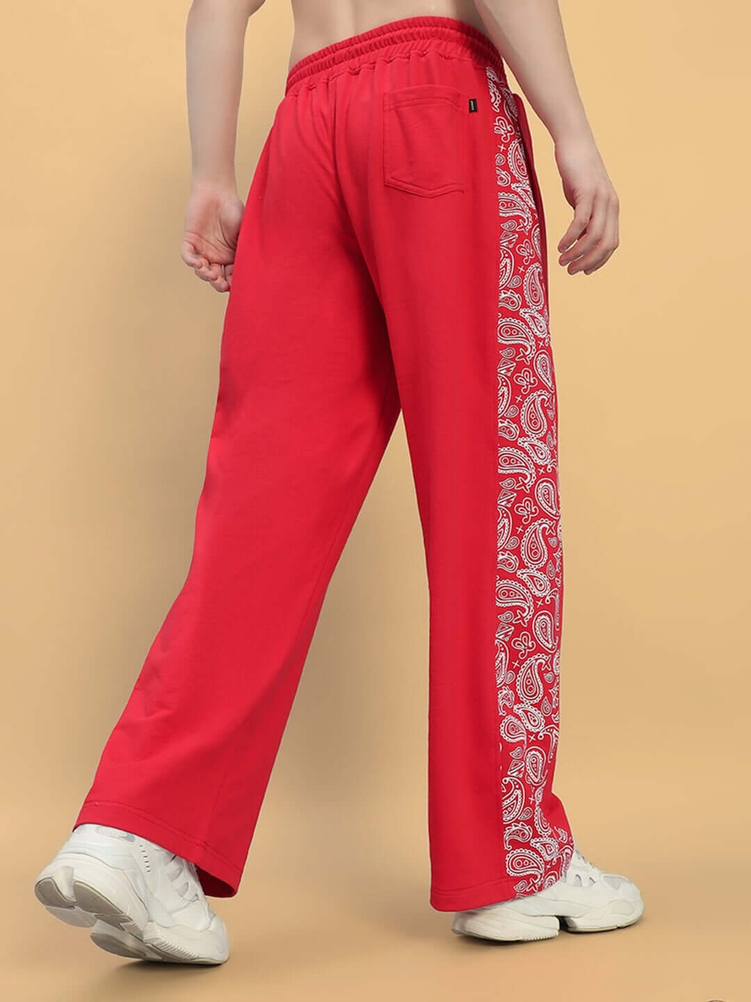 Red relaxed fit joggers with paisley side detailing, made to order by DUDS. Model wearing joggers standing against a neutral background.