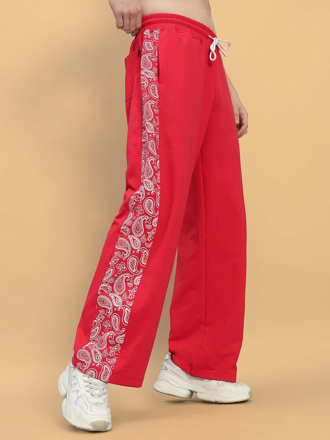 Red relaxed fit joggers with paisley side stripe, worn with white sneakers, showcasing comfortable and stylish design by DUDS.