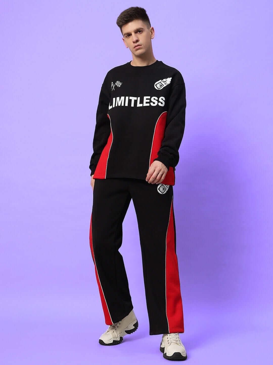 Model wearing WD FIREBALL COLORBLOCK CO-ORD BLACK RED with black-red colorblock hoodie and joggers on a purple background.