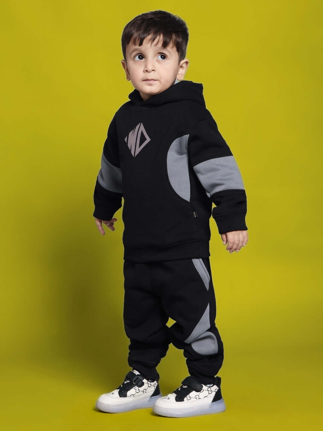 Toddler wearing WD Gorpcore fleece colorblock pants and hoodie in black and grey, against a yellow background.
