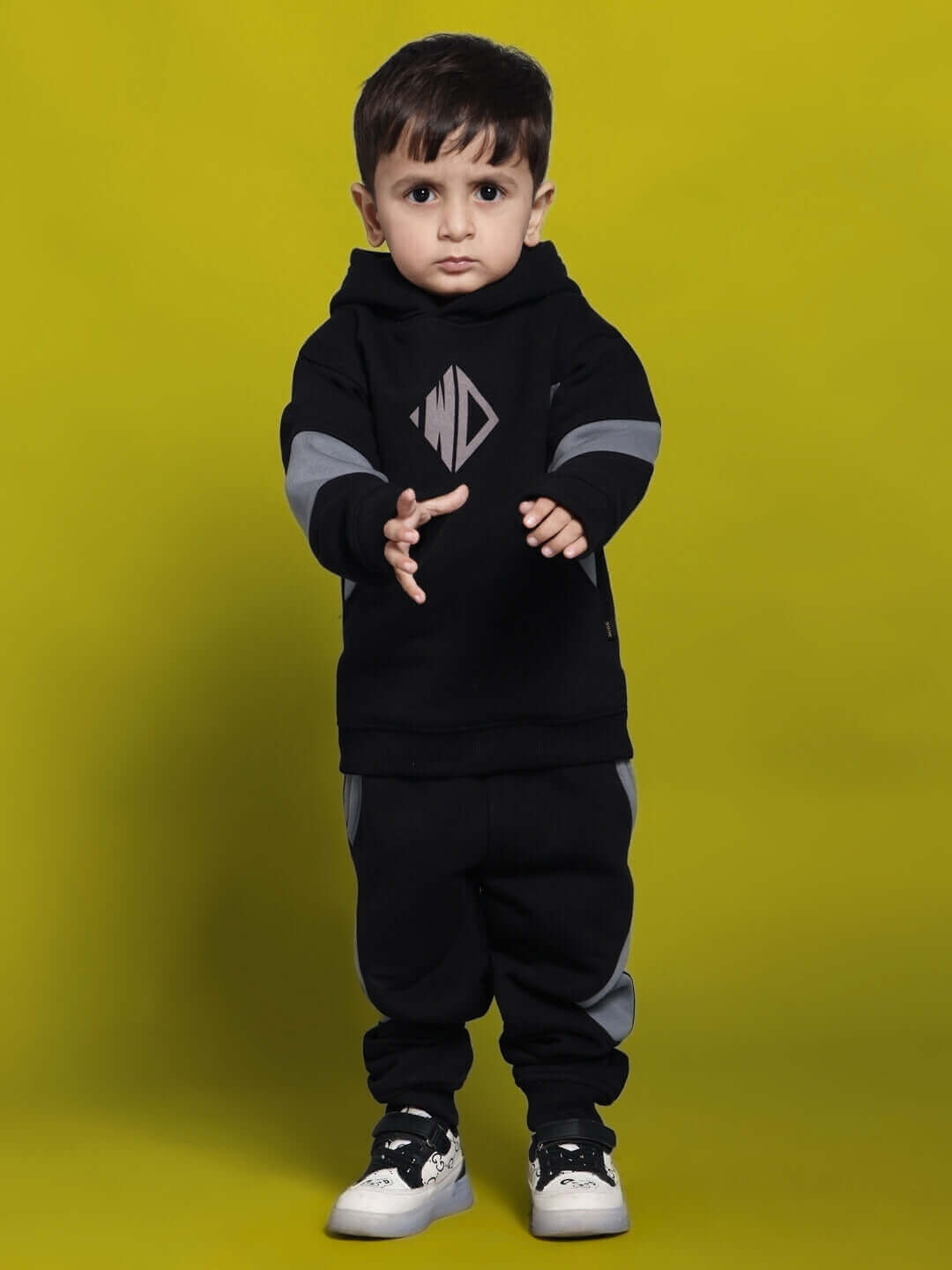 Young child wearing WD Gorpcore fleece colorblock pant and hoodie set for boys and girls, standing against a yellow background.