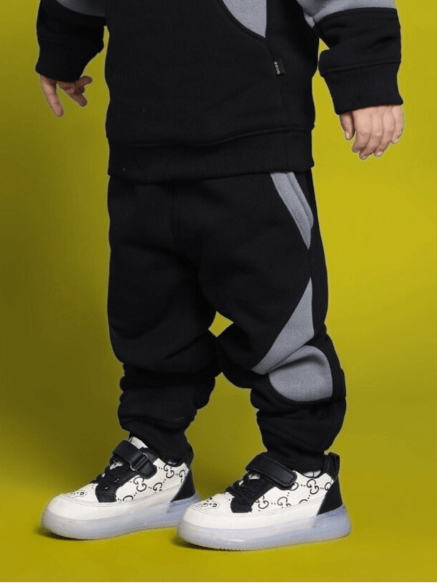 Child wearing WD Gorpcore Fleece Colorblock Pant in black and gray, featuring comfortable design and colorblock style. Made-to-order by DUDS.