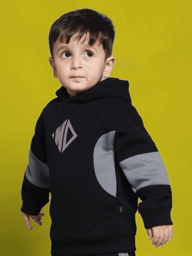 Child wearing WD GORBCORE colorblock fleece hoodie in black-grey against yellow background. Fashion for boys and girls.