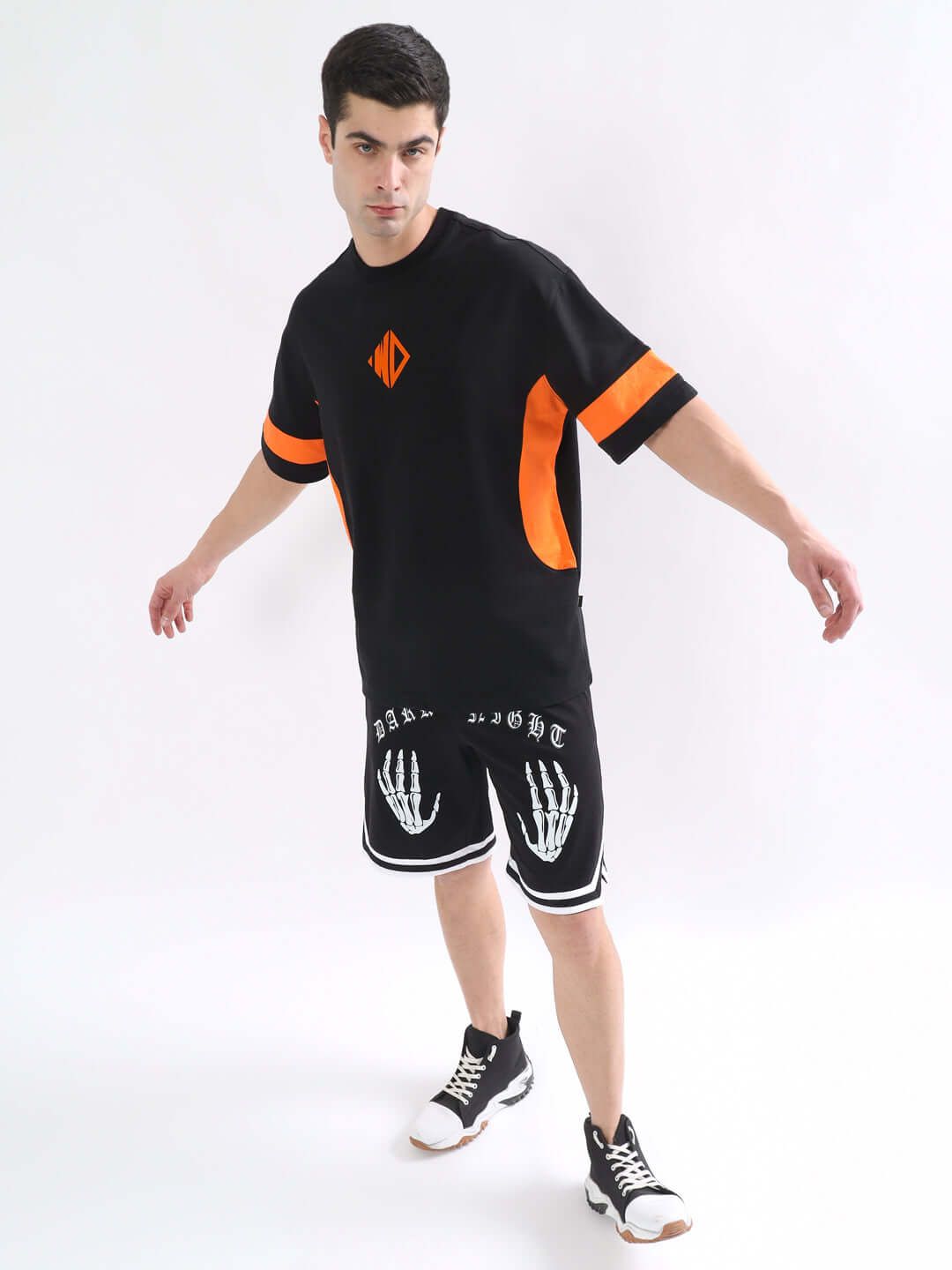 Model wearing WD Gorpcore Oversized T-Shirt in black-orange with premium cotton fabric, styled with black shorts and sneakers.