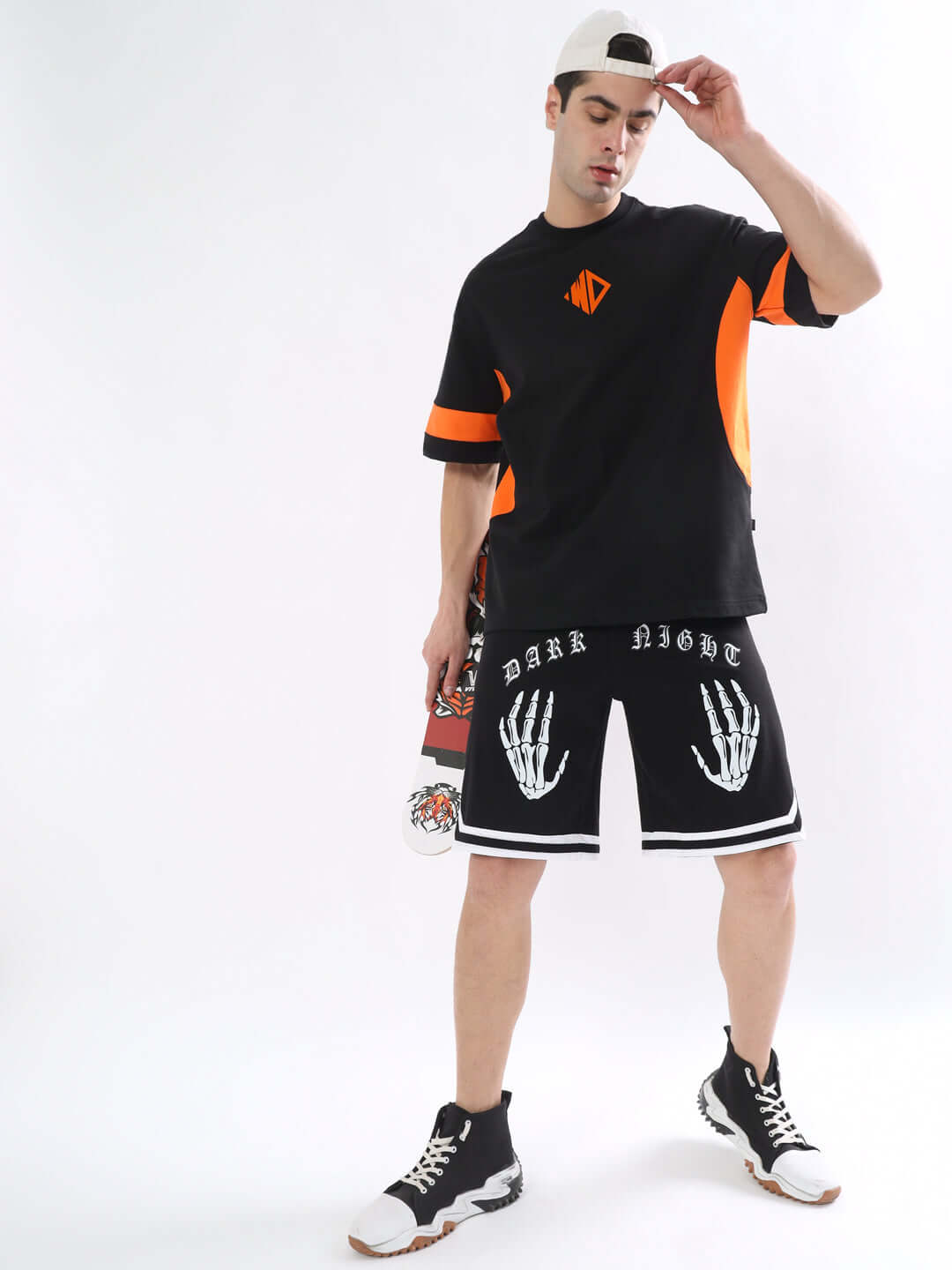 Model wearing WD Gorpcore oversized black-orange T-shirt with graphics, paired with black graphic shorts and sneakers.