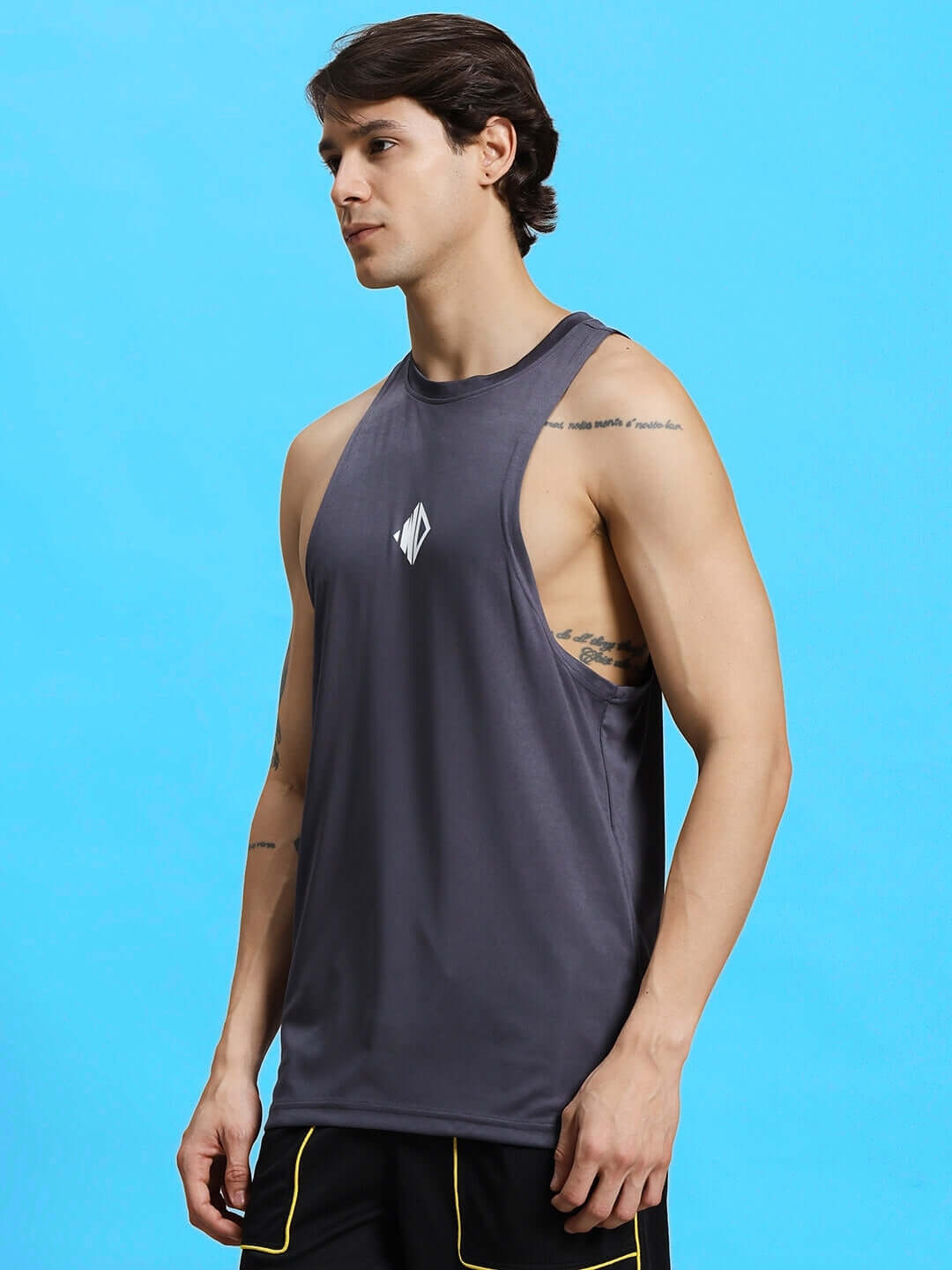 Man wearing WD STRINGER SLEEVELESS GYM T-SHIRT GREY, showcasing sporty fit, against a blue background.