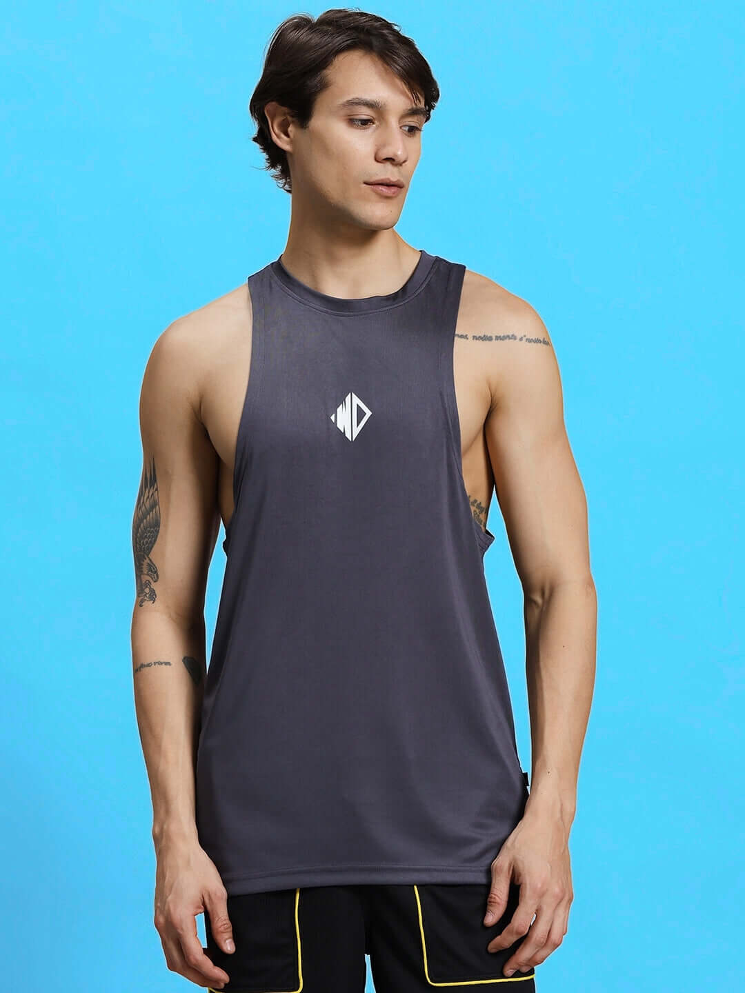 WD STRINGER SLEEVELESS GYM T-SHIRT GREY on model facing left with blue background.