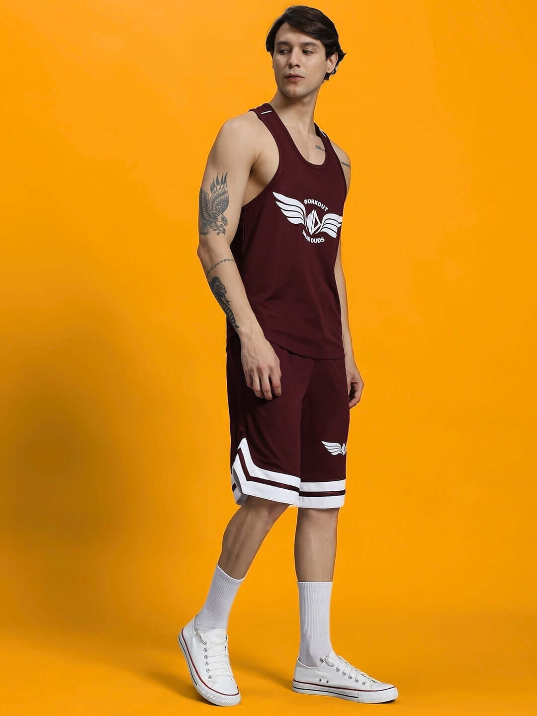Man wearing WD WINGS GYM CO-ORD SET MAROON activewear with maroon tank and shorts against a bright background.